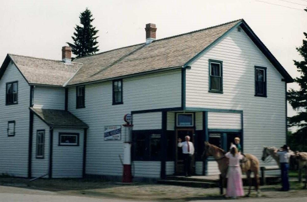 White two-story building with green trim, people and horse in front of Dickson Store Museum.