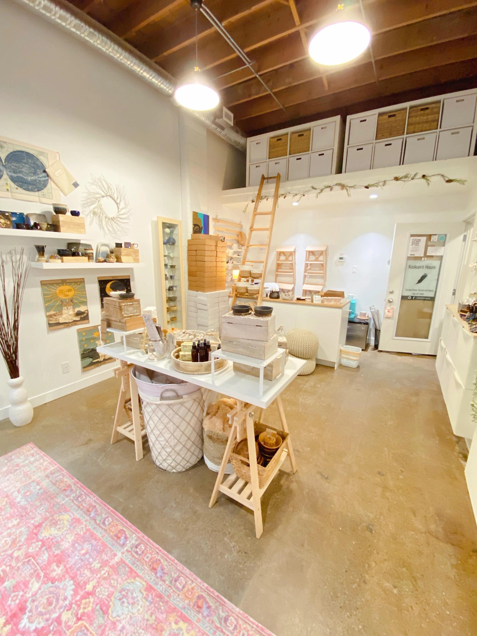 Retail display with shelves, jars, small boxes, and a product counter inside Kookum's House.