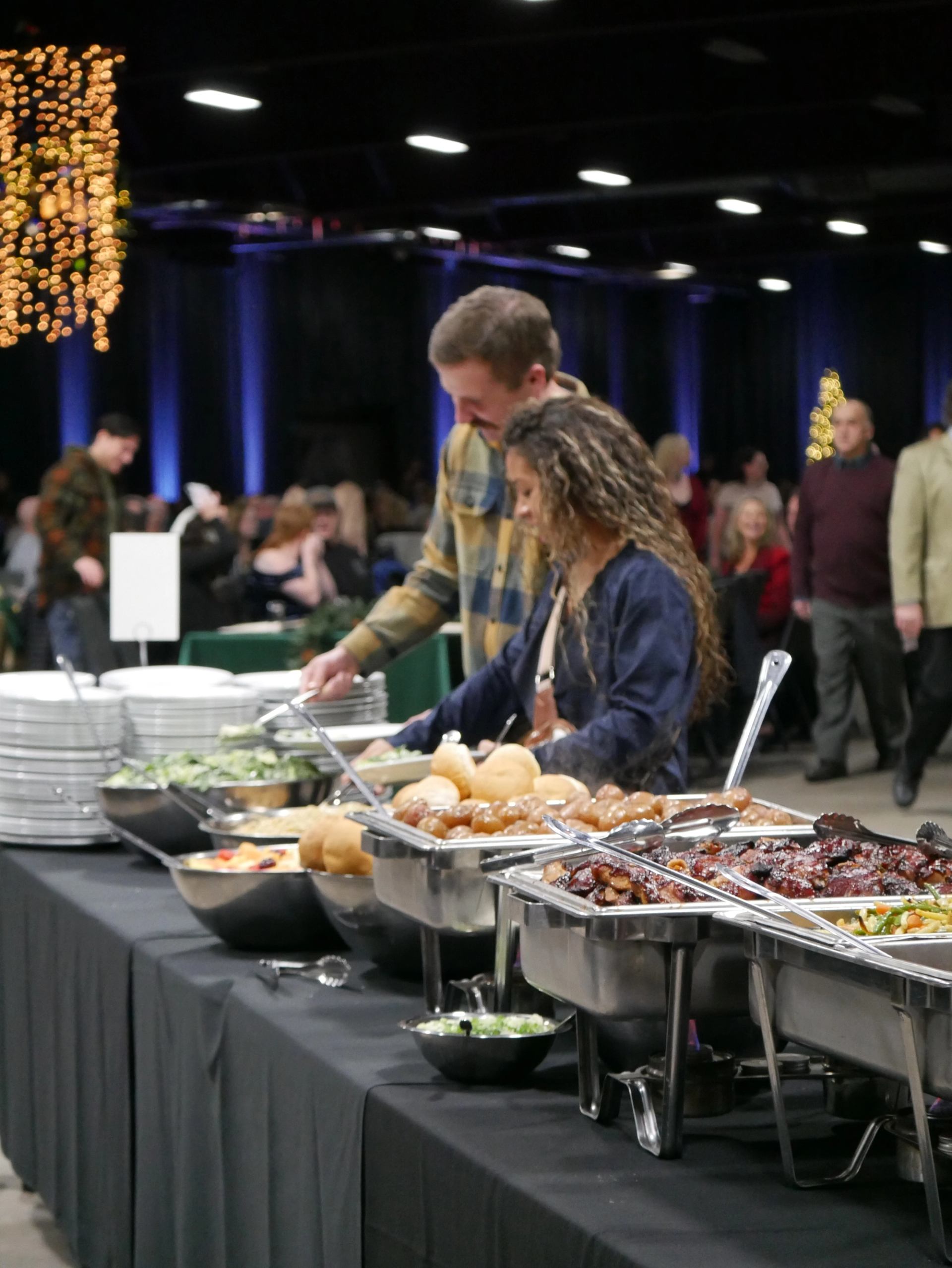 Guests serve themselves from chafing dishes along an indoor buffet table.