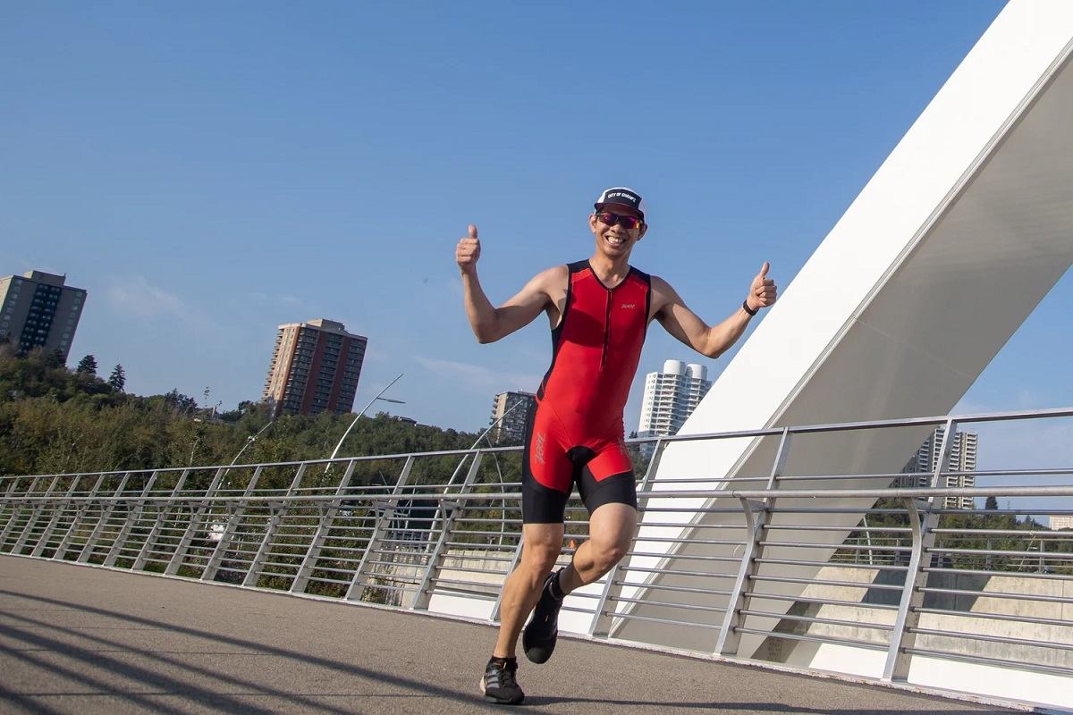 Runner in red gives thumbs up on city bridge during Do North Tri & Trail.