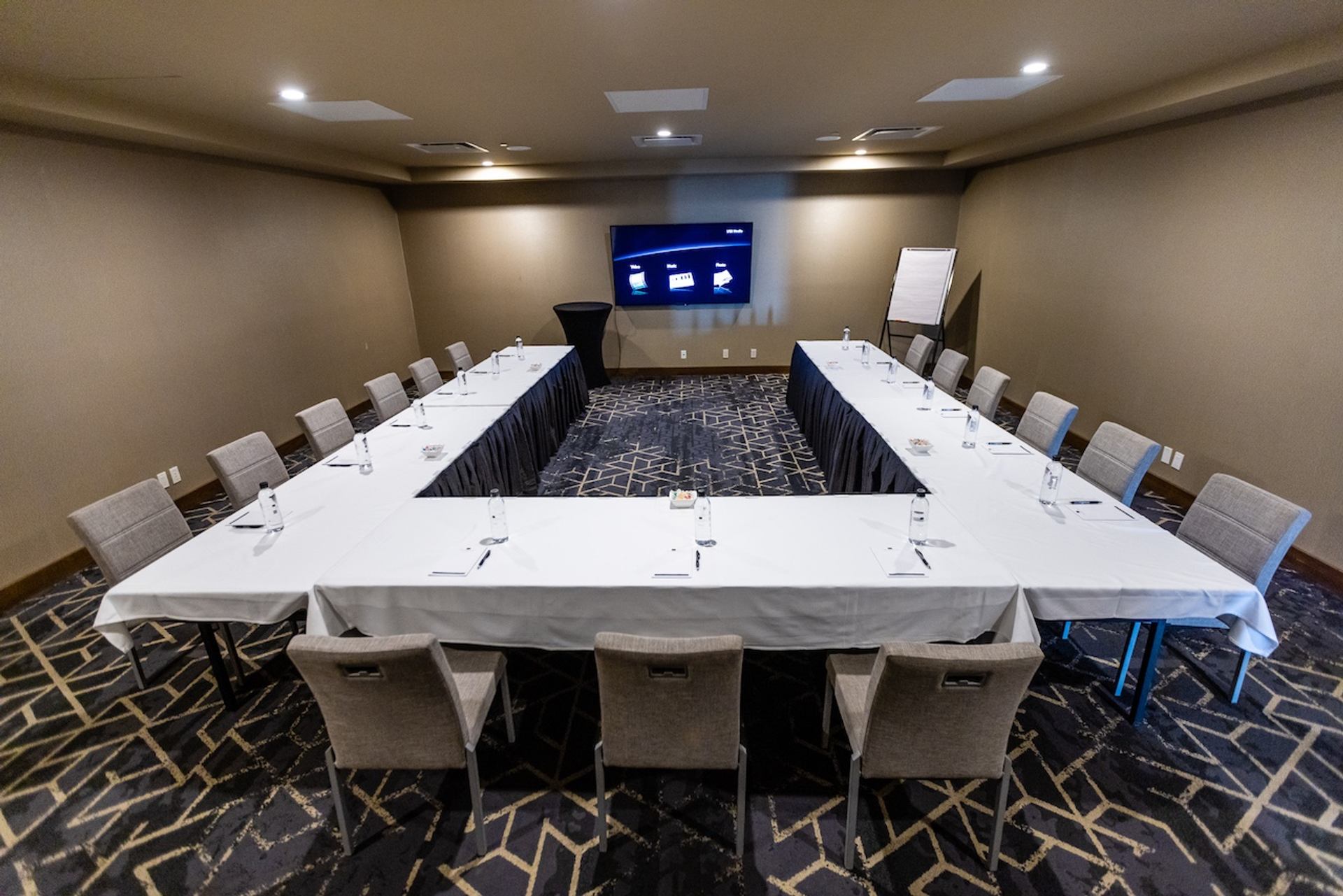  U‑shaped conference setup with chairs and a screen in a private meeting room.