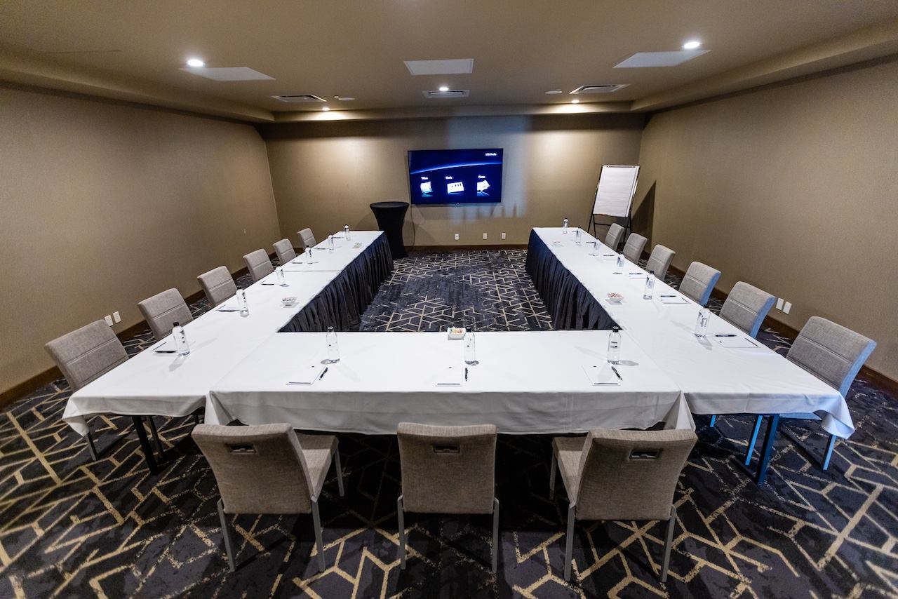 U‑shaped conference setup with chairs and a screen in a private meeting room.