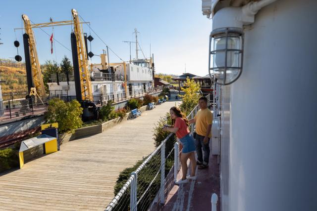 Couple leaning over railing looking at boats at the Fort McMurray Heritage Shipyard.