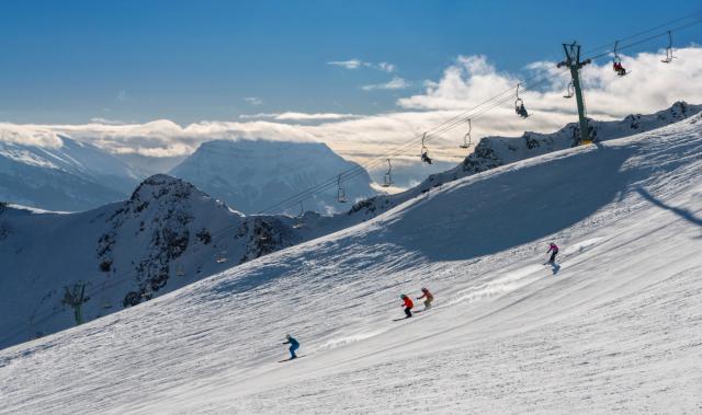 A group of skiers skiing under a chairlift down Marmot Basin in Jasper National Park.