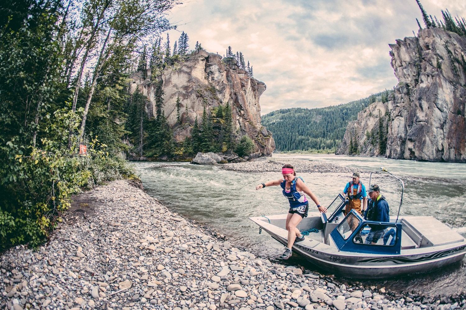 Runner leaps from a boat onto a rocky riverbank during the Canadian Death Race.
