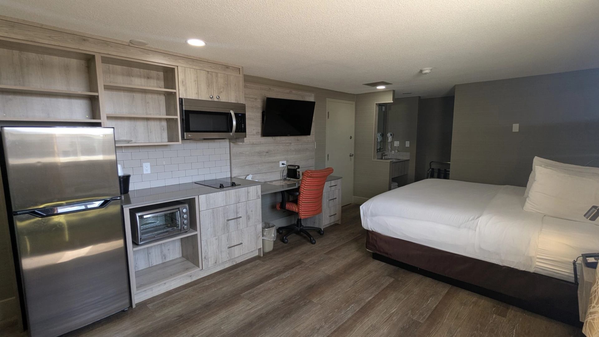 Modern hotel room with bed, kitchenette, desk, and TV at Imperial Inn.