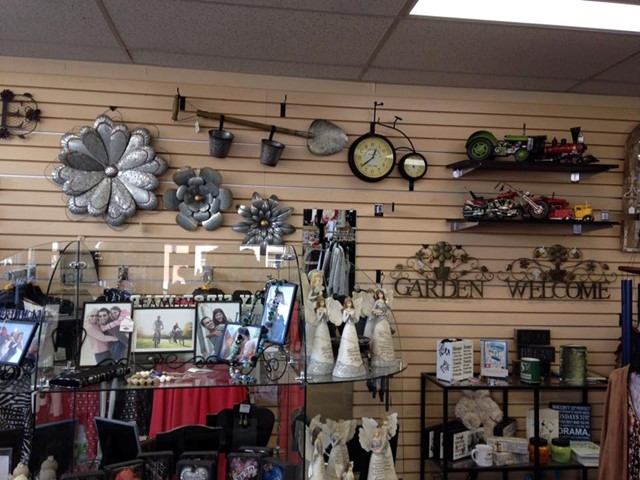 Artisan shop display with garden décor, framed photos, and clocks on wall shelves inside Craig’s Sto.
