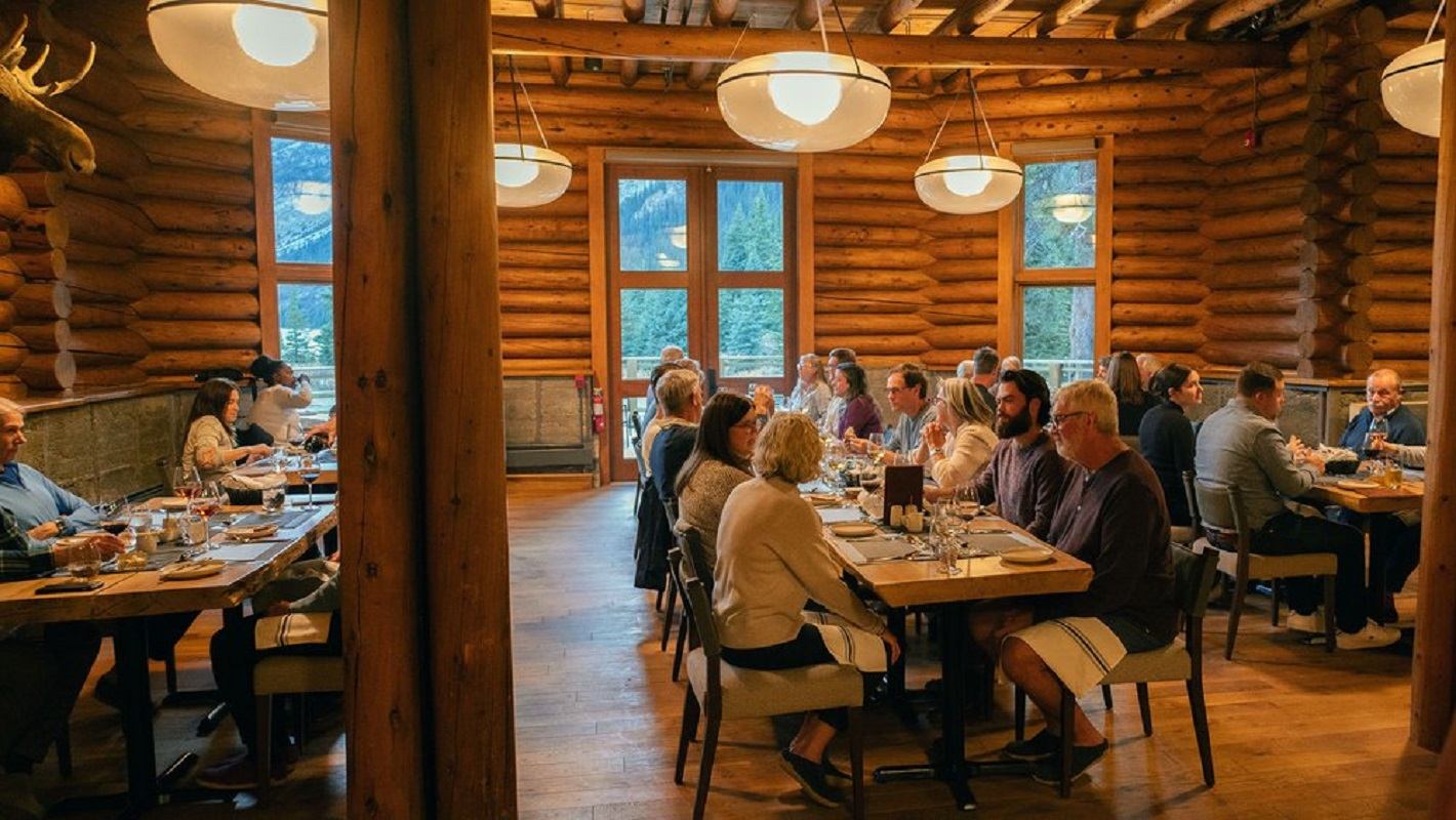 A group of people dining in the rustic room with wooden walls.