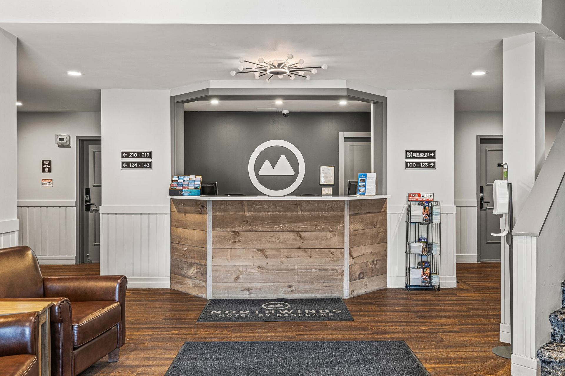 Hotel reception desk with wood panel front, brochures, hallway doors and directional room signs