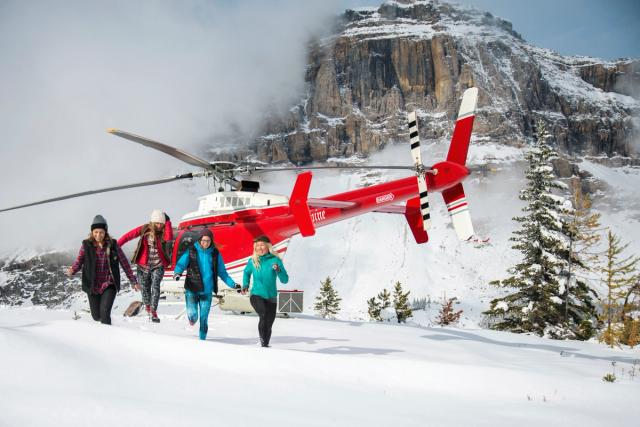 Group of friends walk through the snow on a helicopter tour in Banff National Park