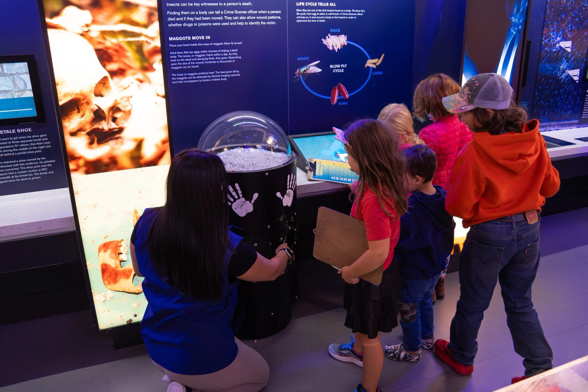 Children gathered around a science exhibit with bright panels and a globe display
