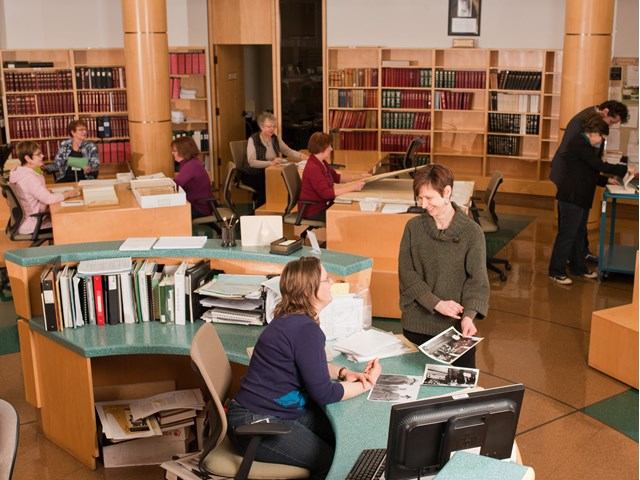 Interior of Provincial Archives with people working at desks, bookshelves, and computers in a study space.