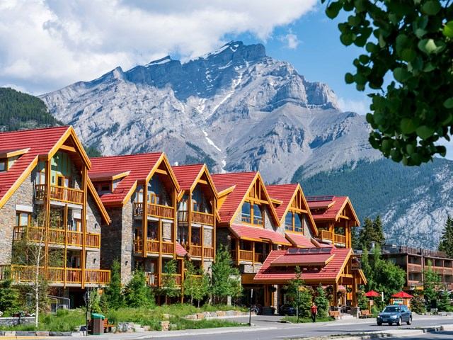 Moose Hotel and Suites with wooden balconies, red roofs, and mountain backdrop.