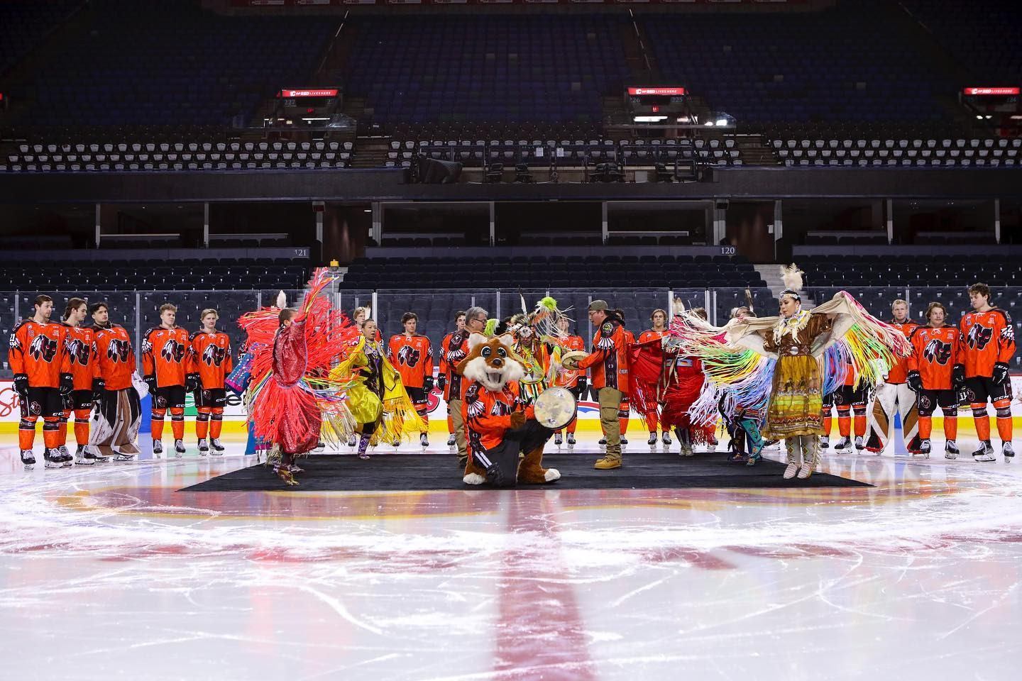 Indigenous dancers and drummers on the ice, during a Calgary Hitmen hockey game at the Scotiabank Saddledome.
