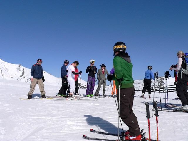 Skiers on a snowy mountain slope under a clear blue sky, ready to hit the trails.