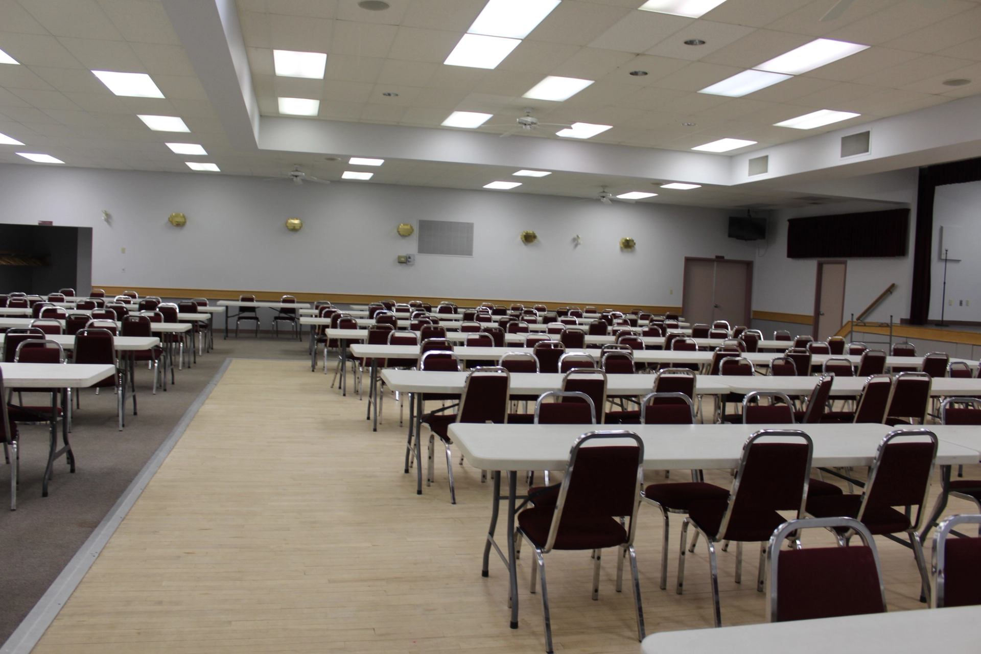 Memorial Hall auditorium with rows of folding chairs and tables under ceiling lights.