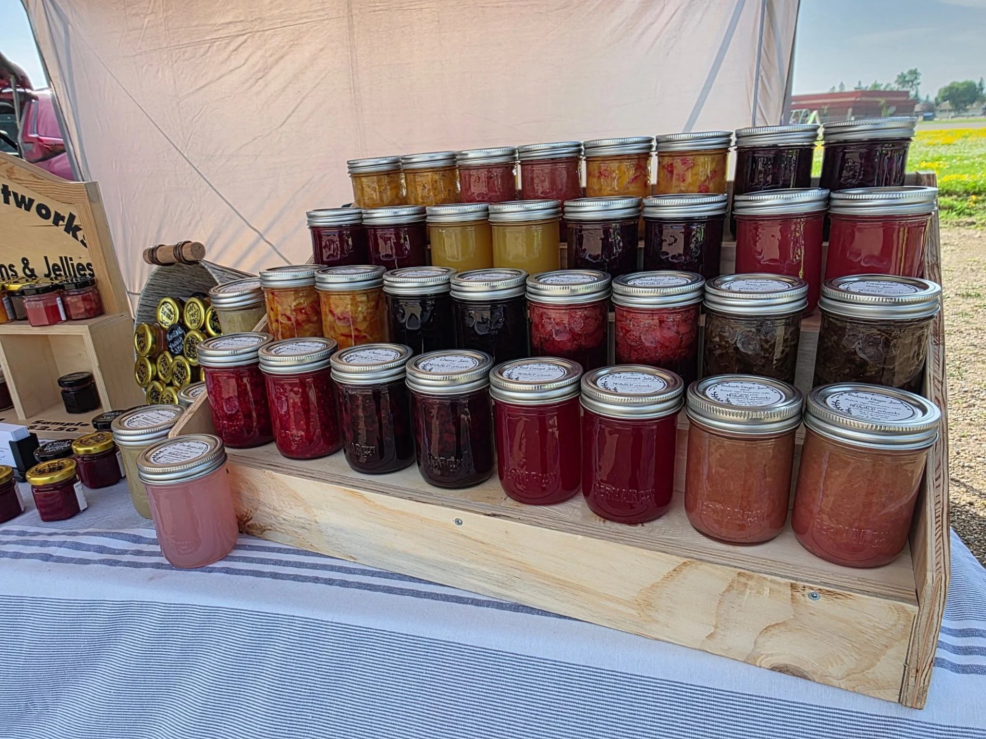 Rows of preserves and jellies in glass jars are arranged on wooden display shelves.