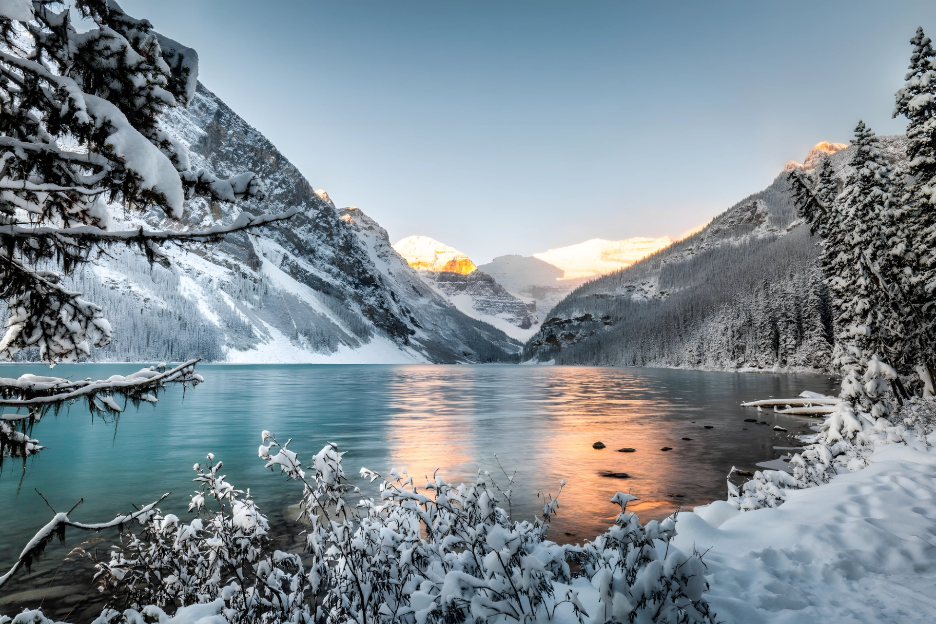 Snowy mountains and turquoise lake at sunrise in Banff National Park.