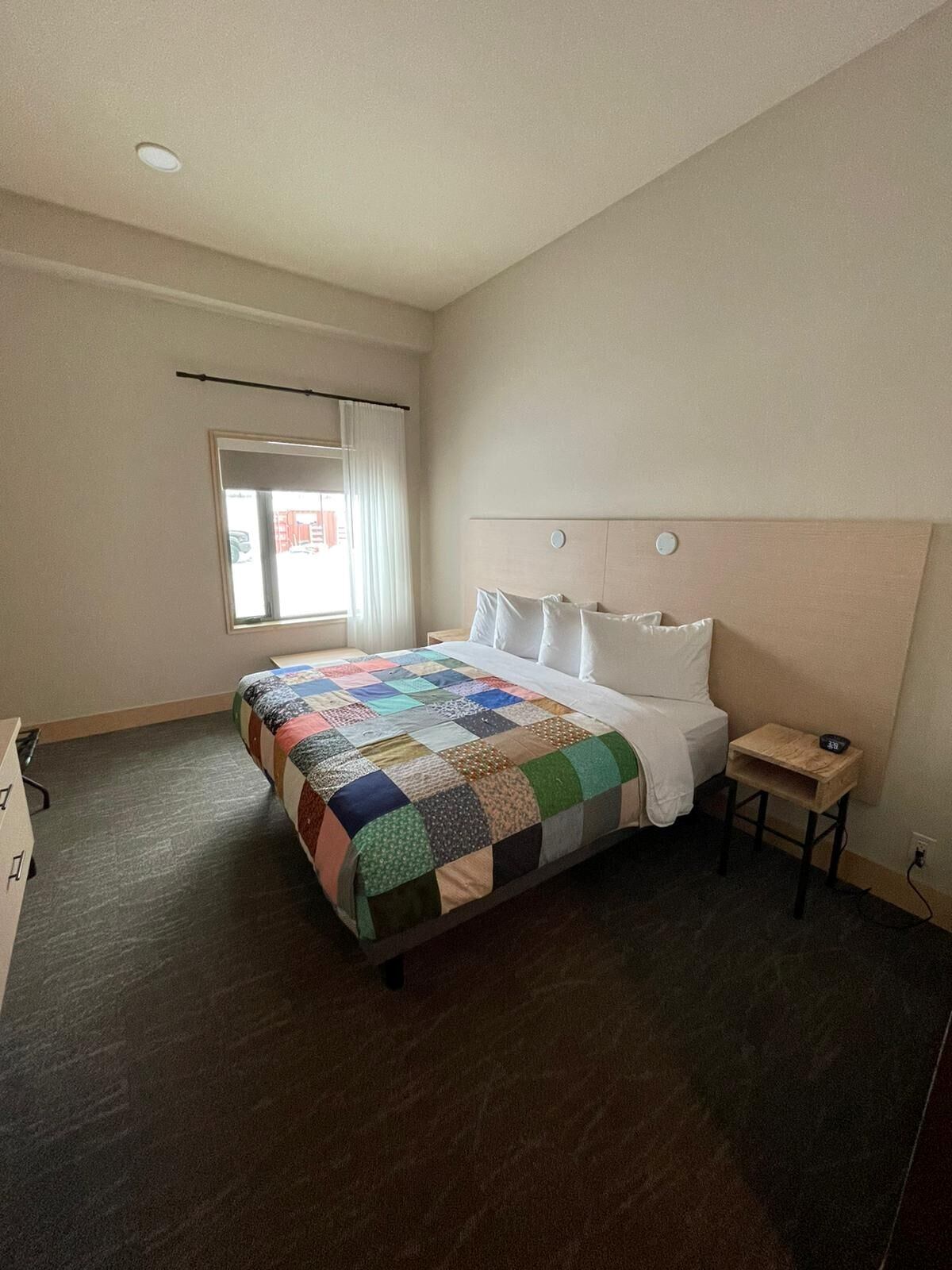 Bed with patchwork quilt, white pillows, and soft light in a cozy Métis Crossing Lodge room.