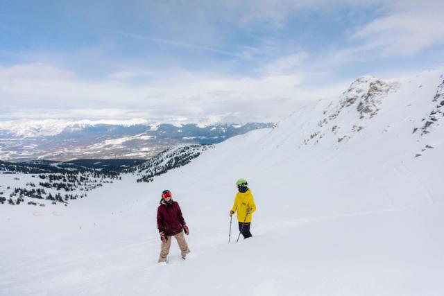 Two people standing and discussing their route before skiing and snowboarding at Marmot Basin in Jasper