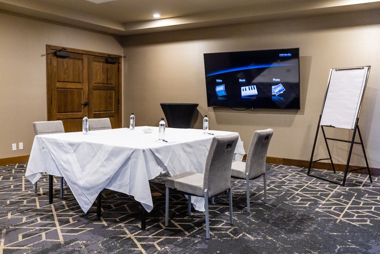 Small meeting room with a square table setup and a large display screen