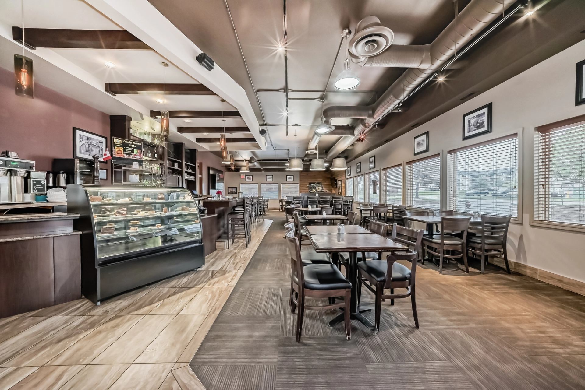  Café-style dining area with tables, chairs, and a glass display counter for baked goods