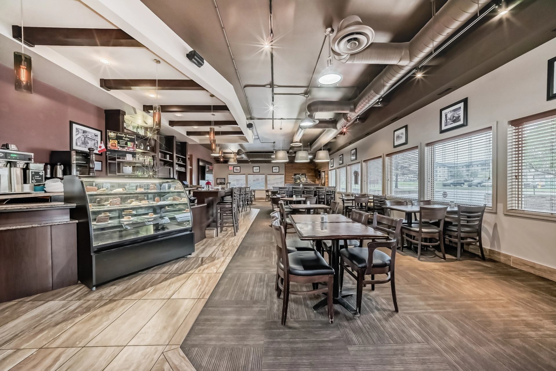 Café-style dining area with tables, chairs, and a glass display counter for baked goods