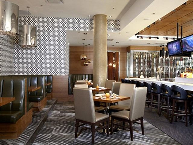 Hotel restaurant with booths, tables, and a bar area in a modern setting.