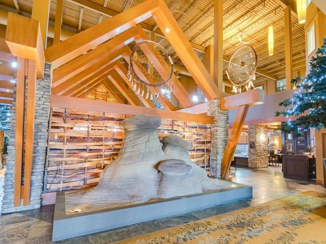 Hotel lobby display with wooden beams, hanging fans, and an illuminated decorative sculpture fountai.