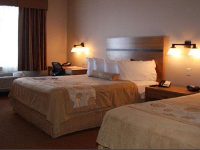 Hotel room with two beds, desk, and warm lighting at Best Western Plus Chateau Inn.