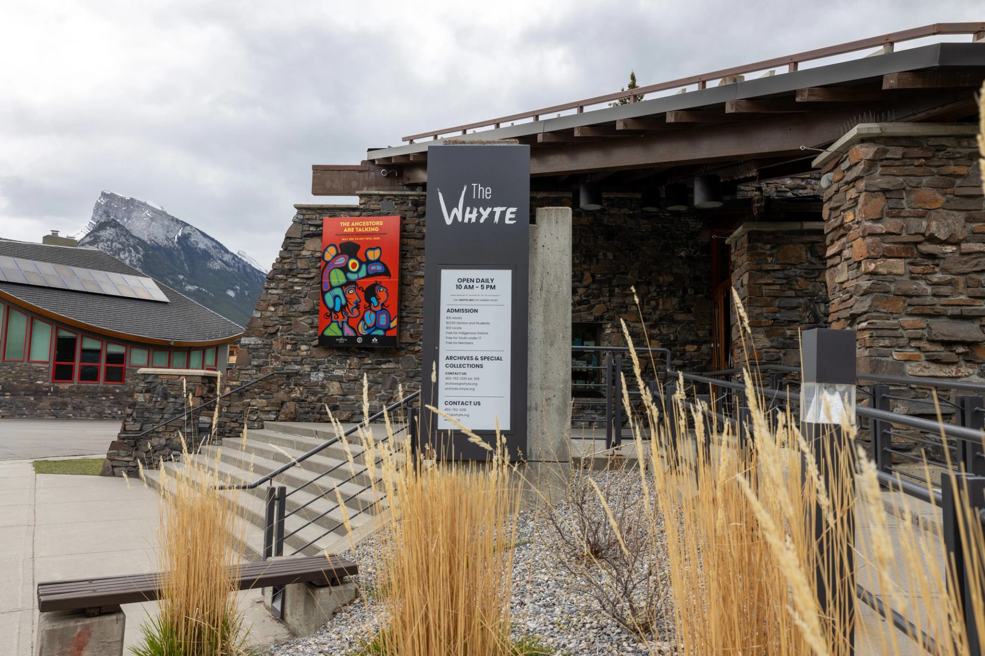 Exterior entrance of The Whyte museum with stone walls and mountain backdrop.