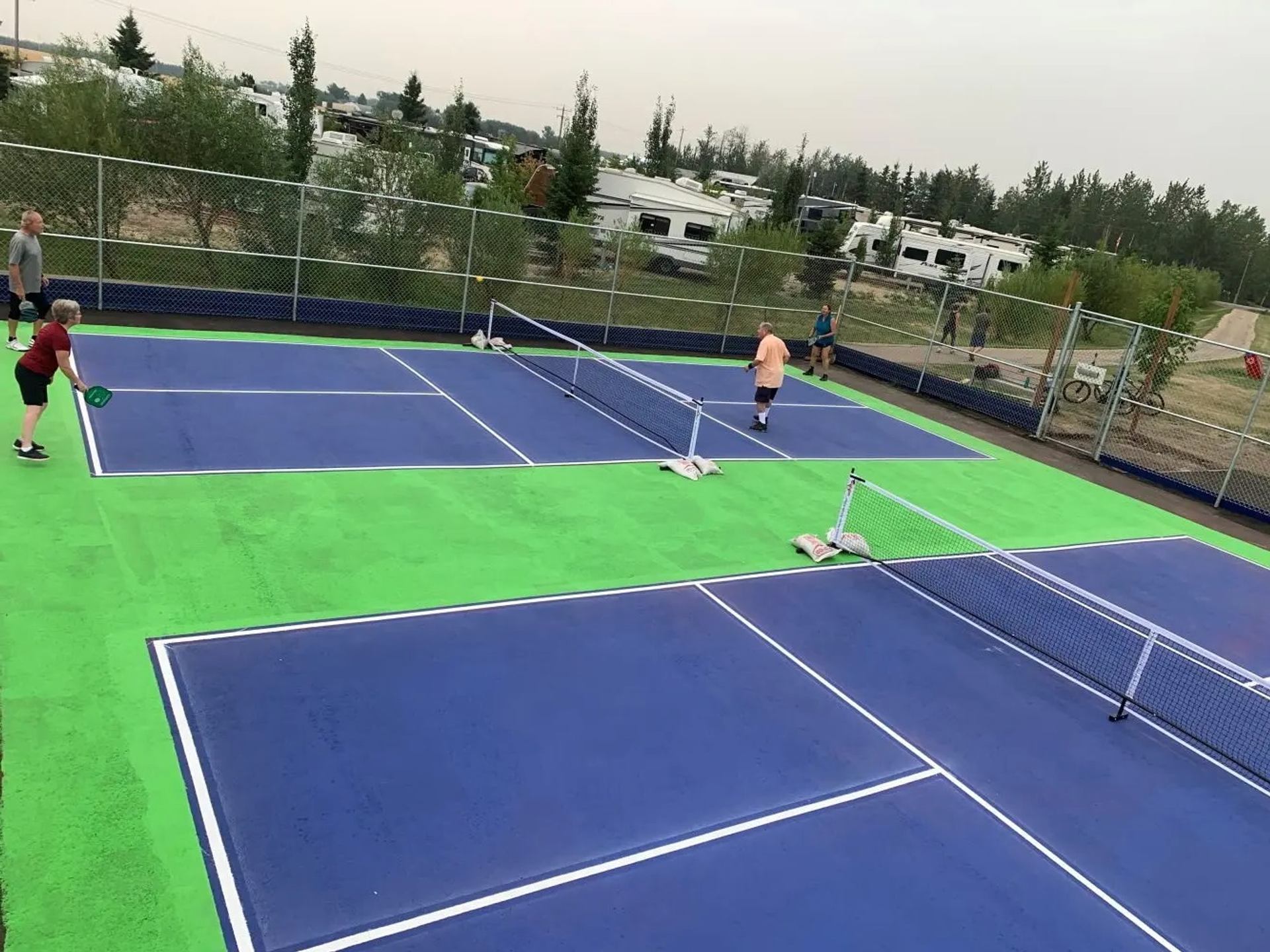People playing pickleball on bright blue and green courts at Leduc Lions Campground.