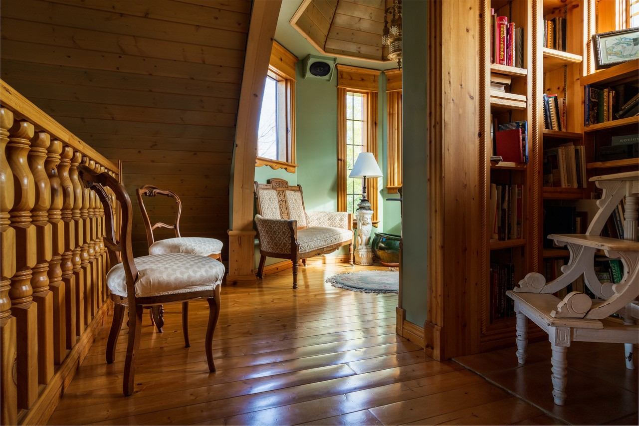 Cozy reading nook with wooden floors, chairs, and built-in bookshelves.