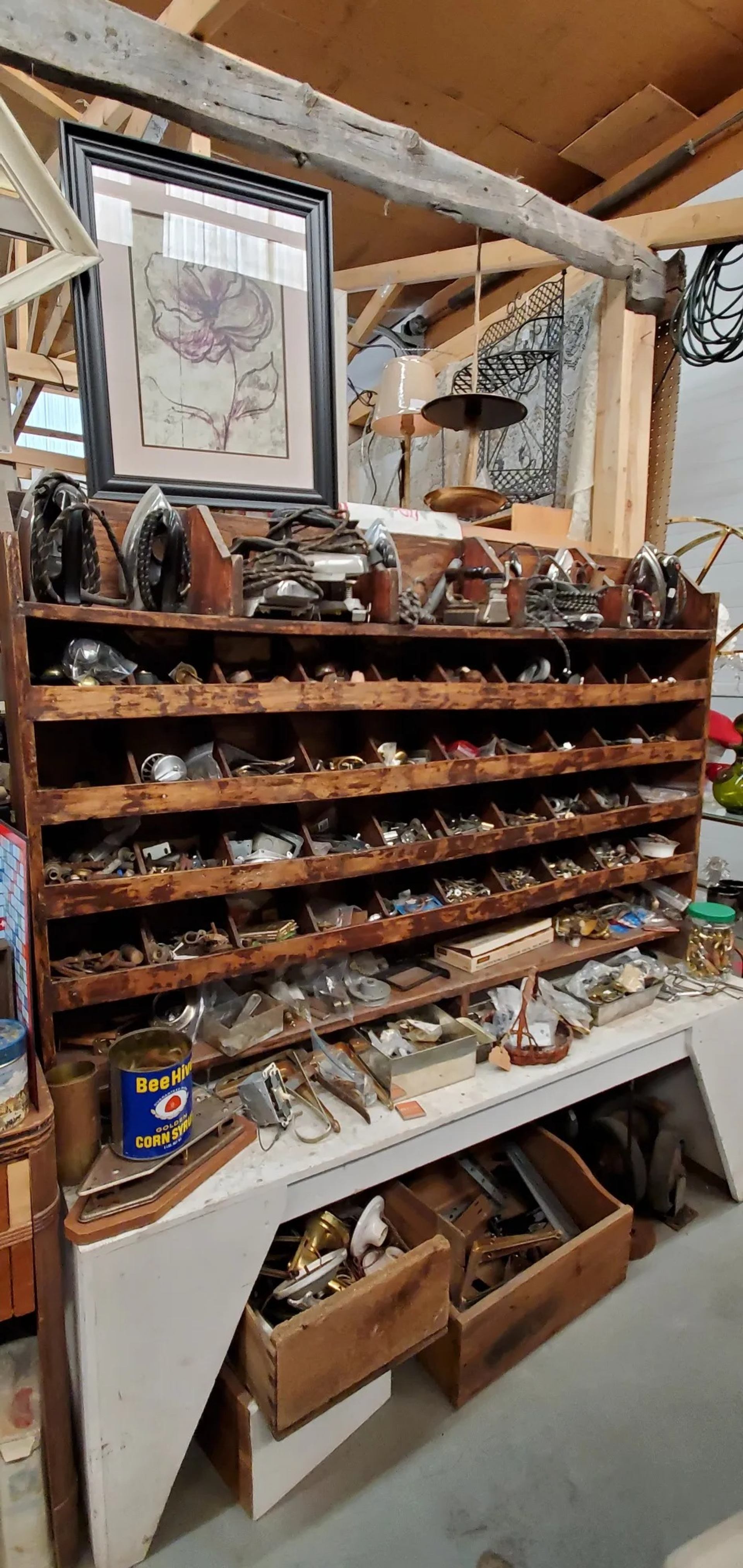 Wooden shelving unit filled with assorted vintage hardware, tools and small metal parts.