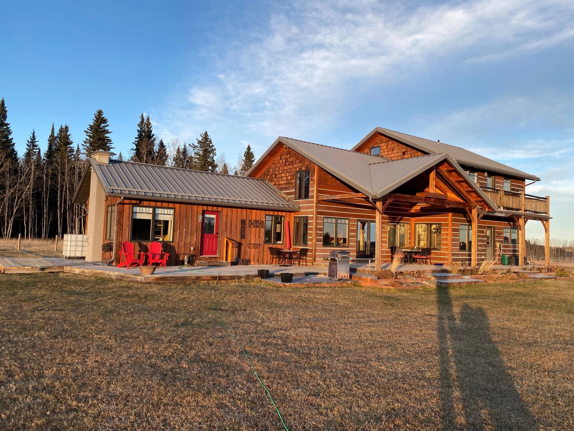 A large log home named KnolLodge featuring an expansive deck and a spacious porch.