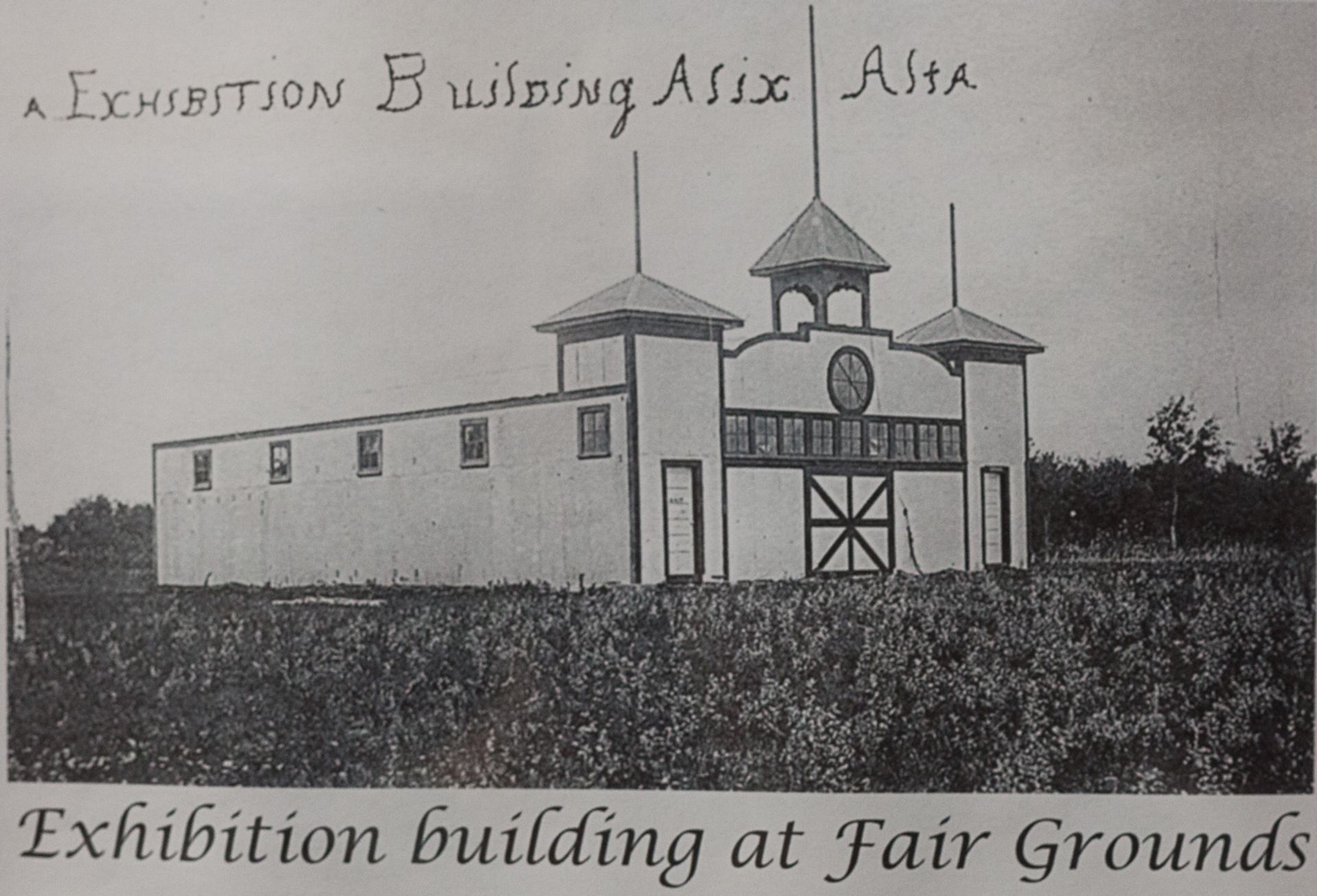Historic illustration of an exhibition building at the Alix fairgrounds with towers and a clock above the entrance.