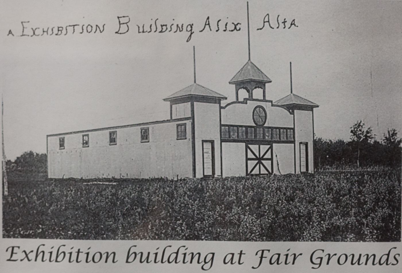 Historic illustration of an exhibition building at the Alix fairgrounds with towers and a clock above the entrance.