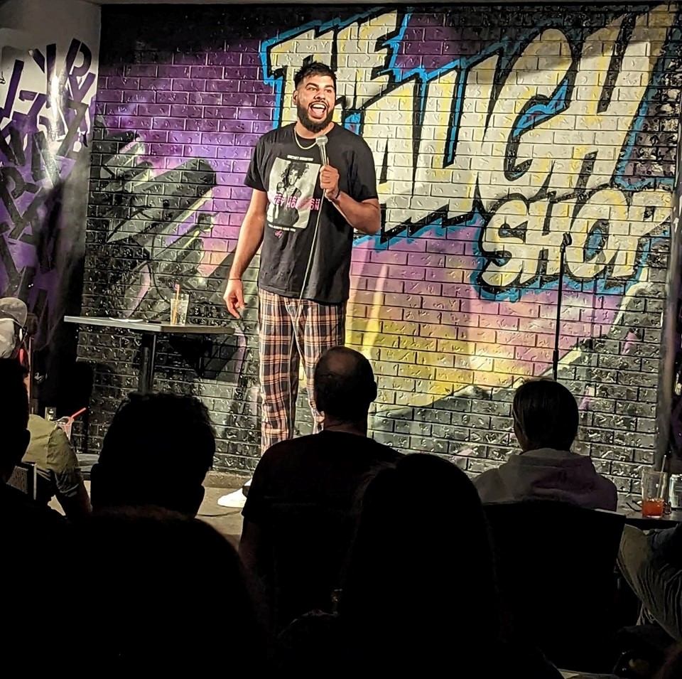 The Laugh Shop stage with comic and urban backdrop.