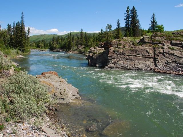 Clear river flowing between rocky banks and pine trees at Greenford Provincial Recreation Area.