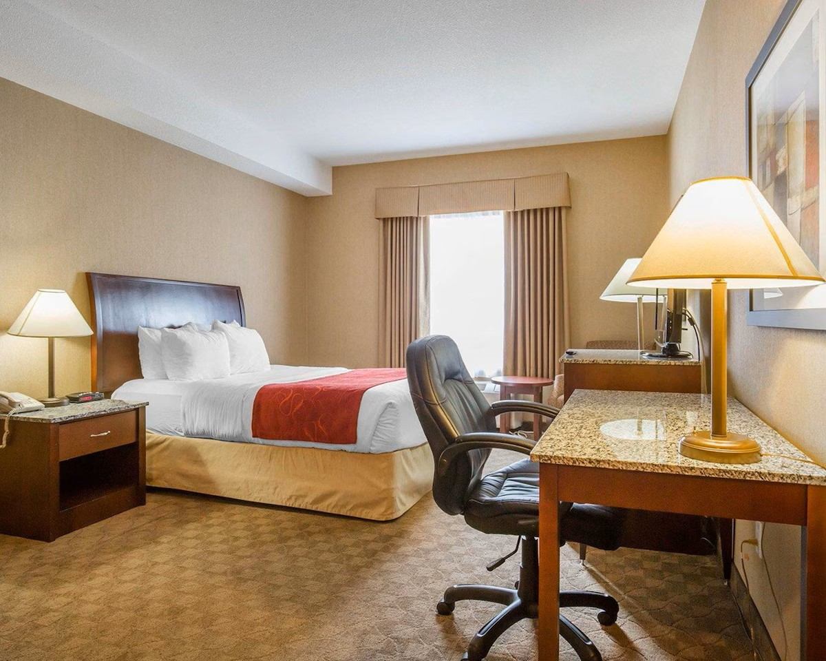 Comfort Inn & Suites guest room with a king bed, work desk, chair, and warm lighting.