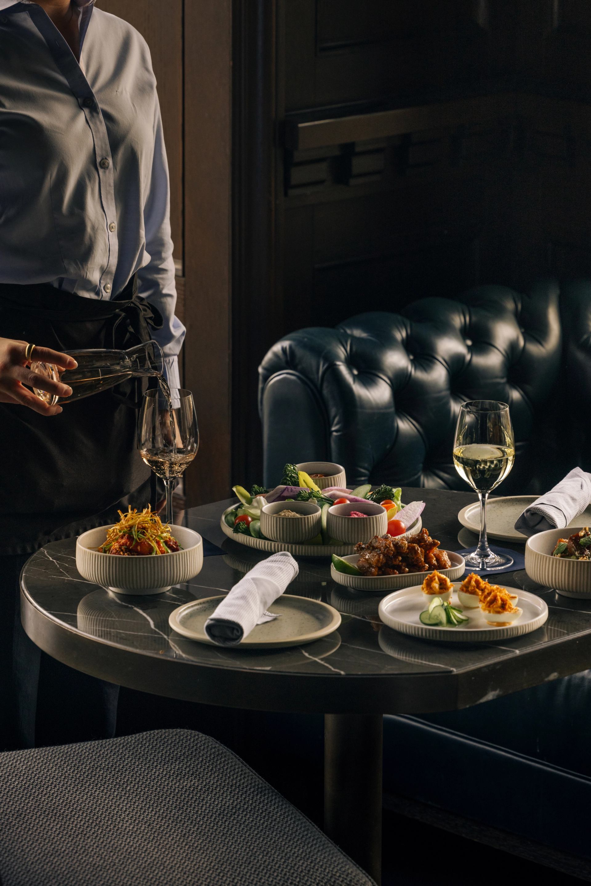 Table with plated dishes, wine glasses, and napkins in a dimly lit, elegant setting.
