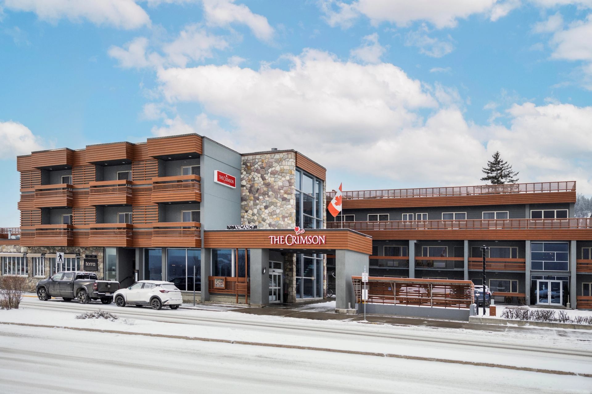 Crimson Jasper hotel facade with balconies, stone wall, and Canadian flag outside.