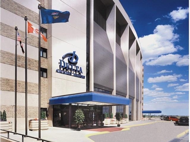 Exterior of Delta Calgary Airport hotel with flags, blue canopy, and modern design.