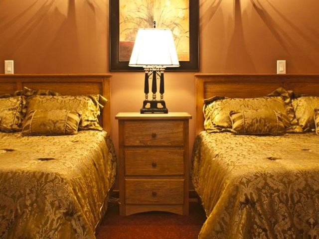 Twin beds with patterned bedspreads, nightstands, and a table lamp in a hotel room.