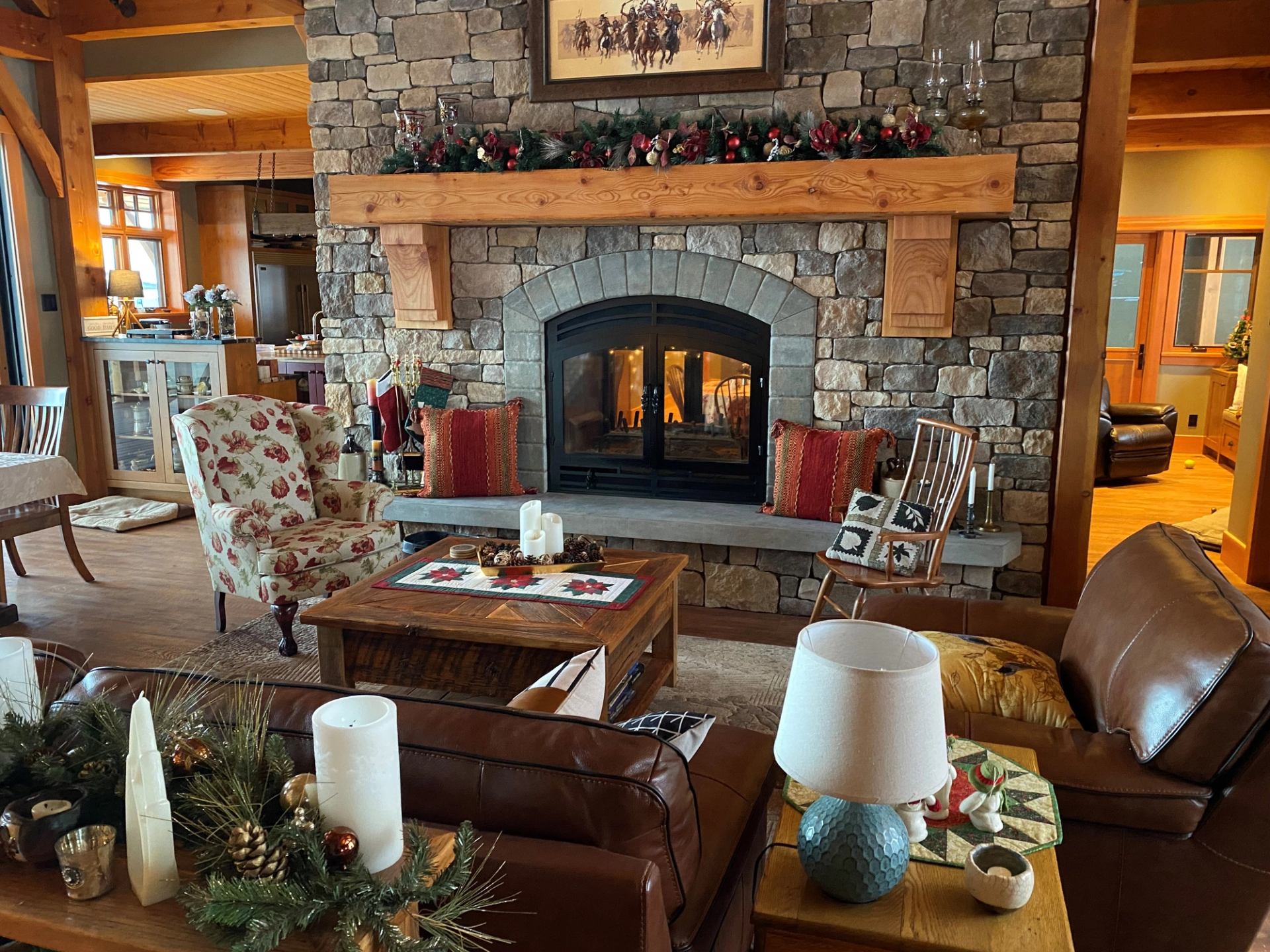 Warm living room with stone fireplace, festive decor, and rustic furnishings.