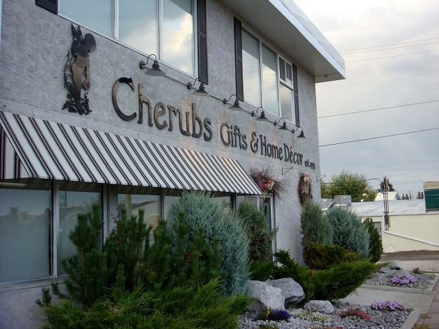 Cherubs Gifts & Home Decor storefront with awning, shrubs, and garden rocks outside.
