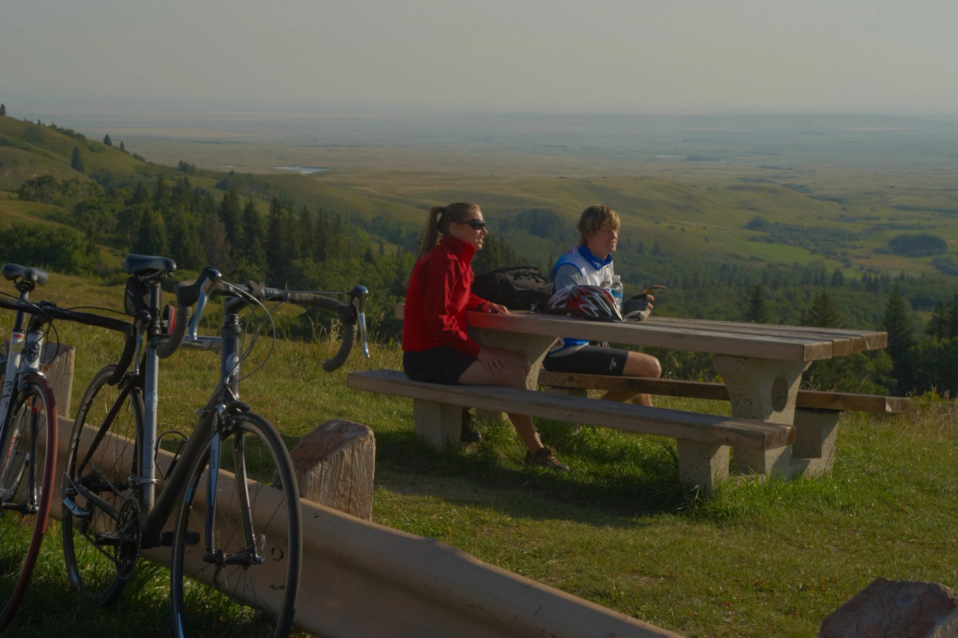 Two people sitting at a picnic table taking a break from biking.