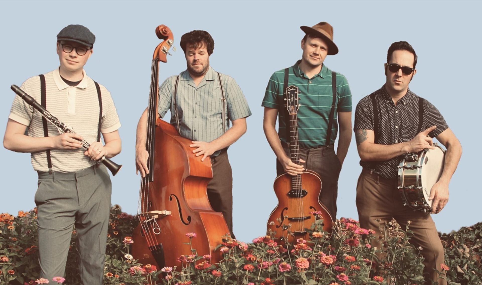Four musicians with instruments stand behind flowers against a plain light blue background.