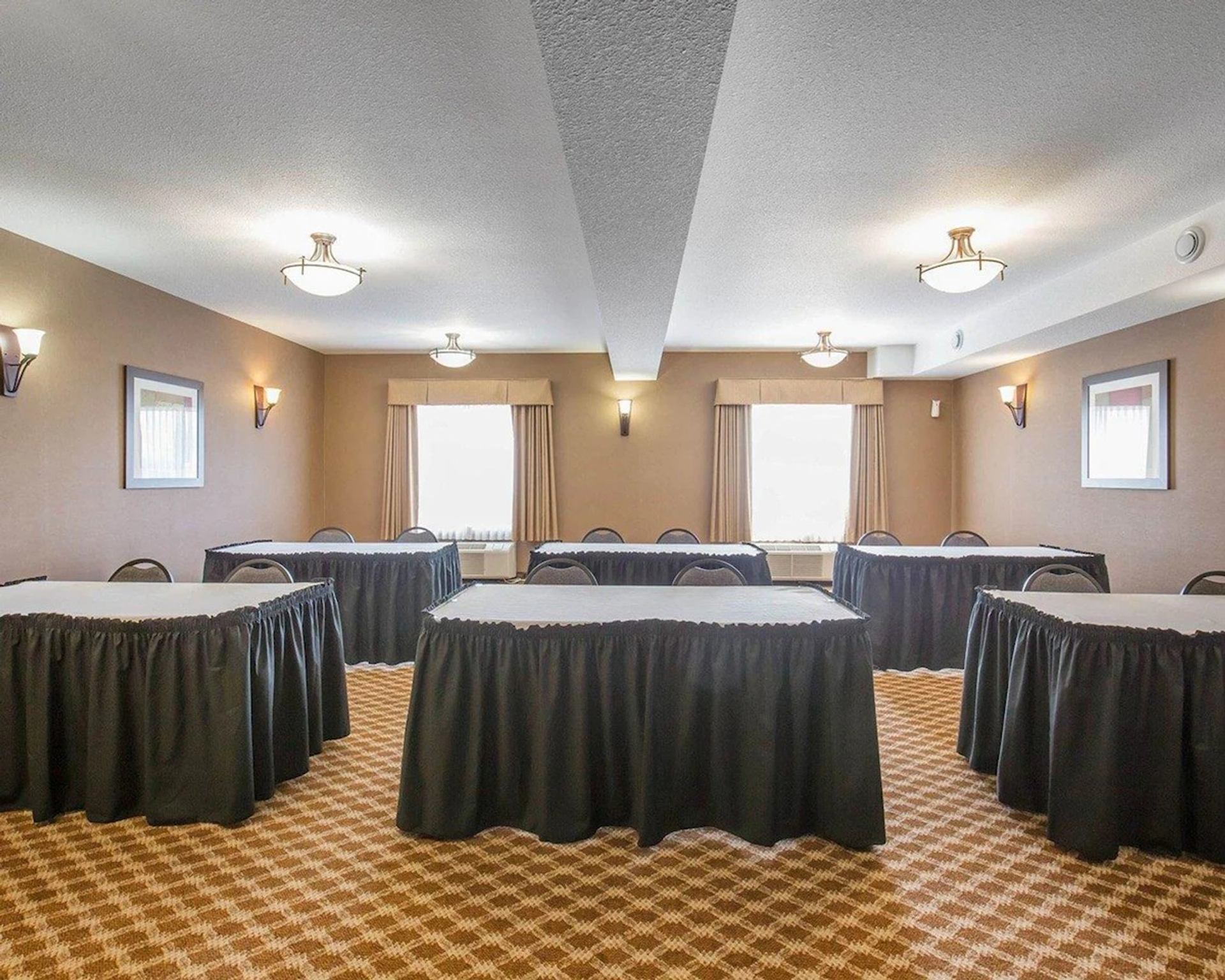 Meeting room at Comfort Inn & Suites with conference tables, chairs, and natural light.