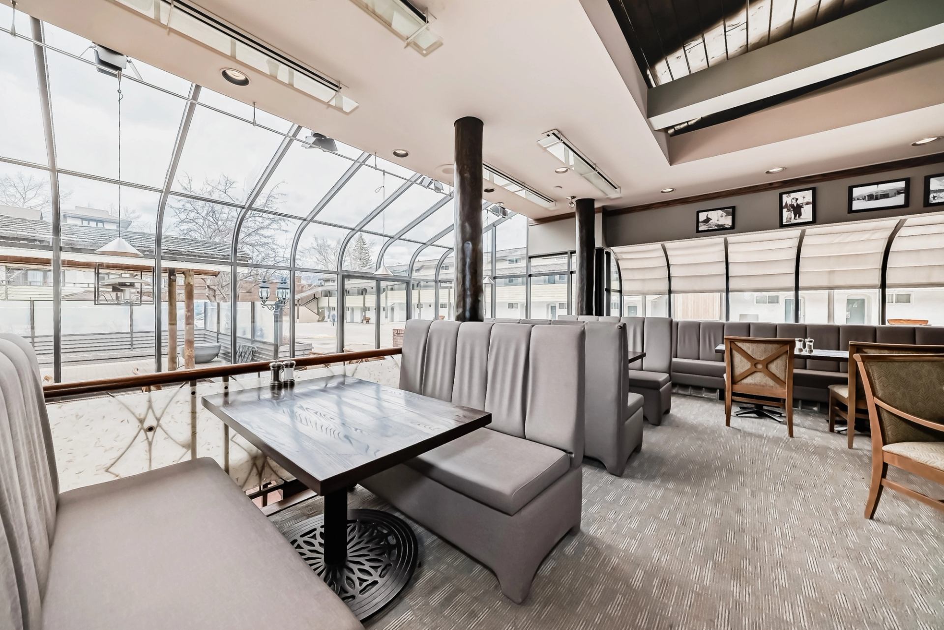 Dining space with booth seating, glass walls, and outdoor view under natural sunlight